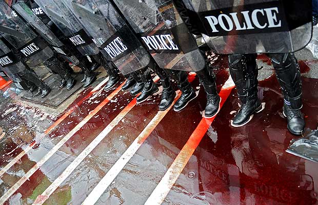 Oddział policji stoi w kałuży krwi wylanej przez Czerwone Koszule na ulicy Bangkoku. Wtedy jeszcze krew polała się zgodnie z planem: została zebrana od ochotników i wylana m.in. przed parlamentem. W ostatnią sobotę to się zmieniło (Zdjęcie: vancouversun.com)